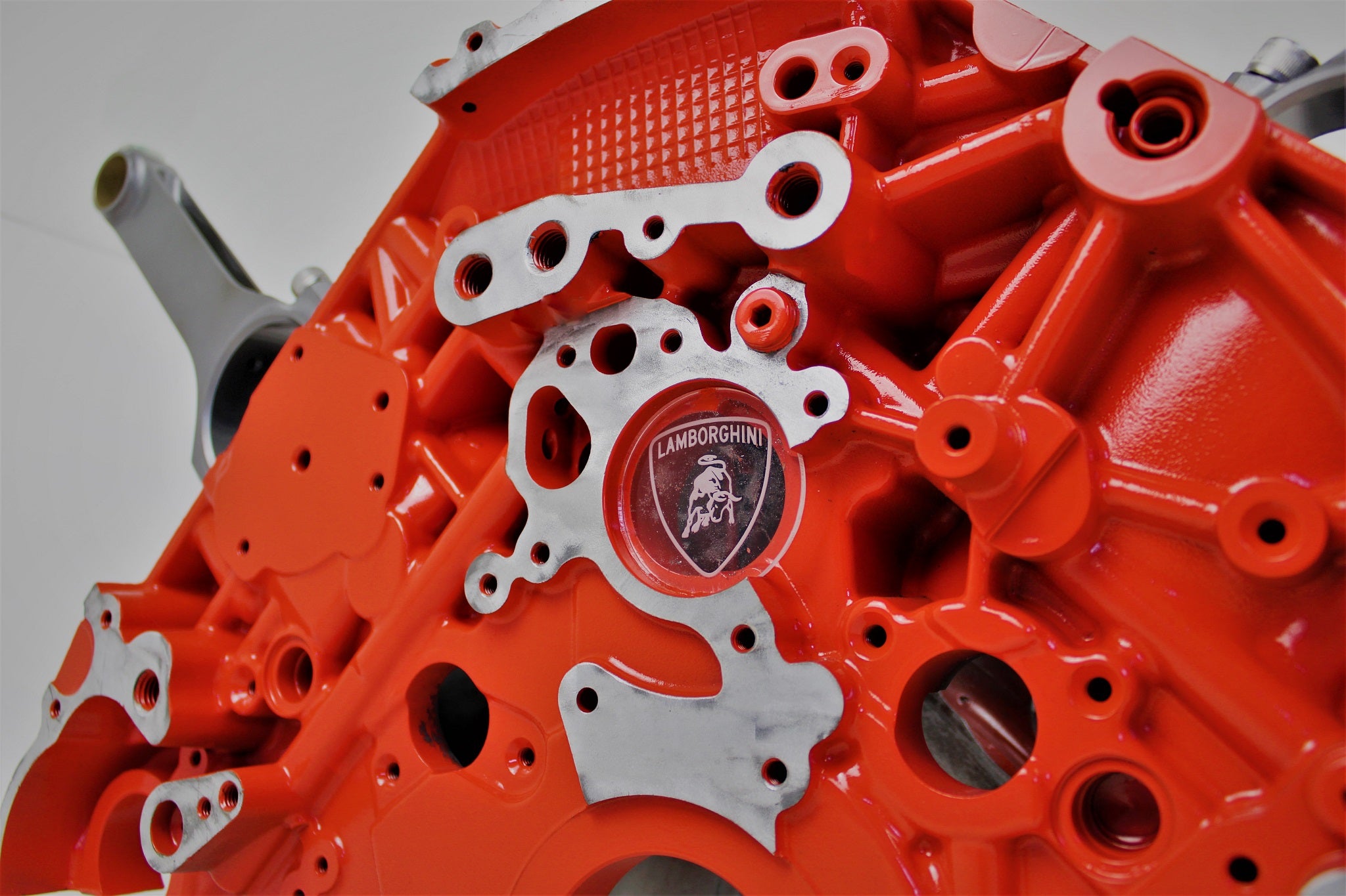 Close-up view of a Lamborghini Gallardo V10 engine block coffee table finished in orange with a square glass top.