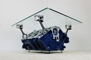 Bentley engine block coffee table with a rectangular glass top held up by car engine pistons. The table is painted dark blue, with the Bentley logo displayed on the front.