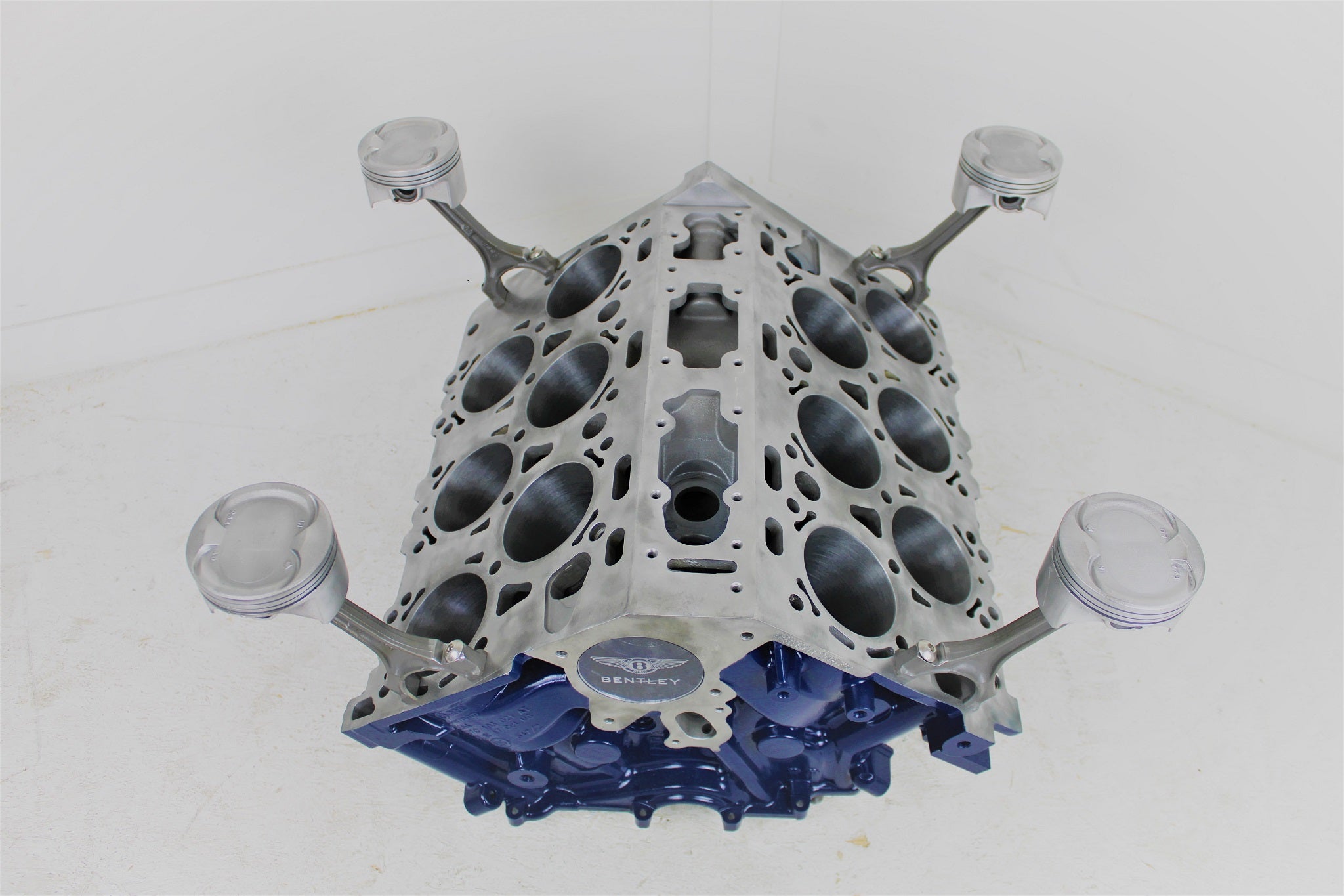 Bentley engine block coffee table without its glass top. The table is painted dark blue, with the Bentley logo displayed on the front.