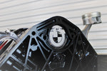 Load image into Gallery viewer, A close-up of the BMW logo on a BMW M Series V10 engine block coffee table painted in the BMW M-Power color scheme without its glass top.
