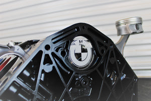 A close-up of the BMW logo on a BMW M Series V10 engine block coffee table painted in the BMW M-Power color scheme without its glass top.