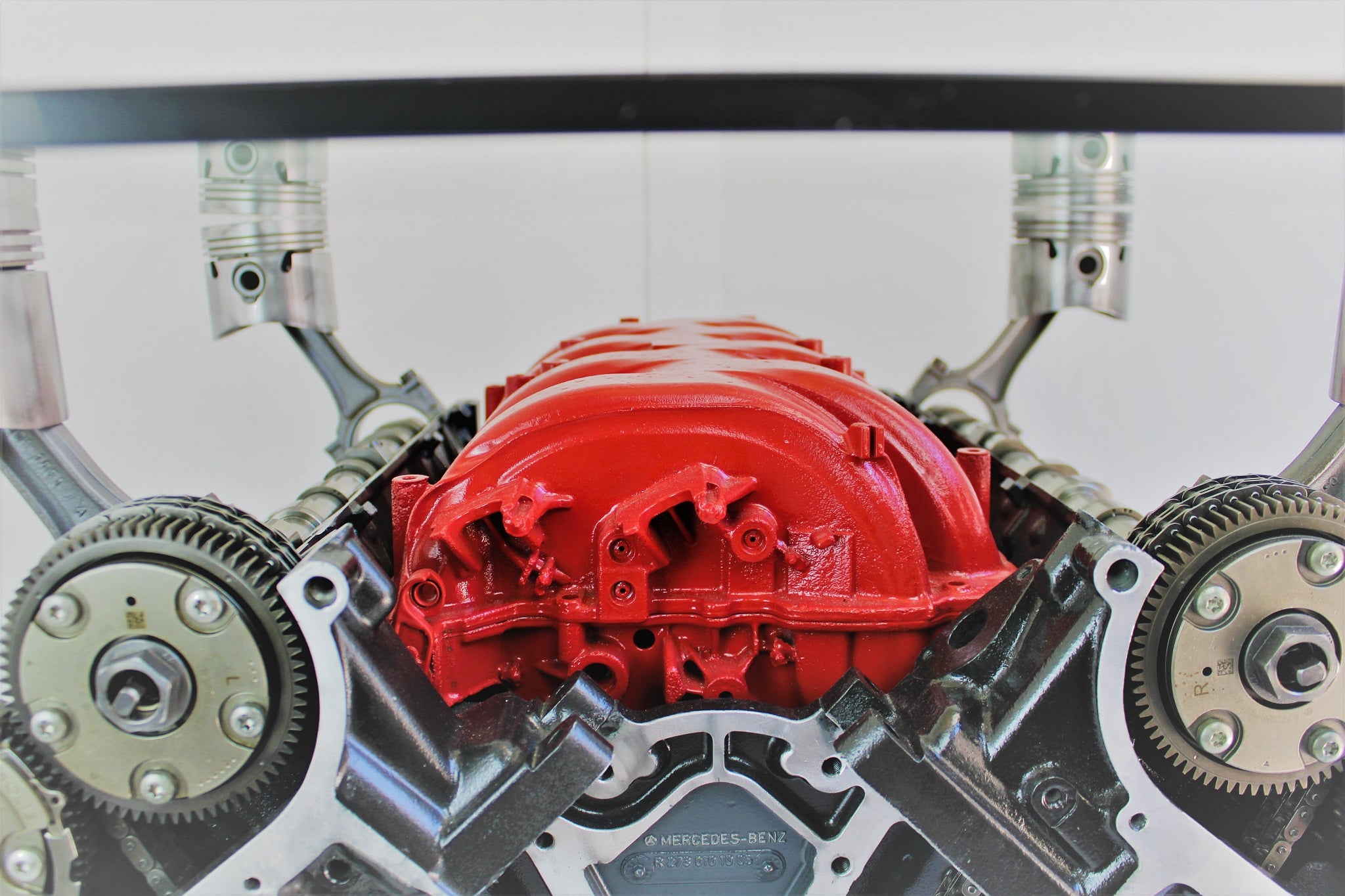 Close-up view of an intricate engine block coffee table finished in red, black and silver, the Mercedes Benz logo displayed in the center.
