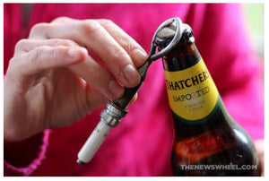 Someone opening a beer bottle with a spark plug bottle opener.