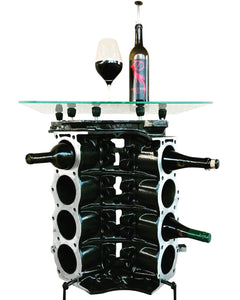 Engine block wine rack finished in black with a square glass top, wine bottles stored in its side and a wine bottle and glass on top.