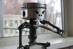 Load image into Gallery viewer, Piston man car part sculpture sitting on a windowsill holding a wrench.
