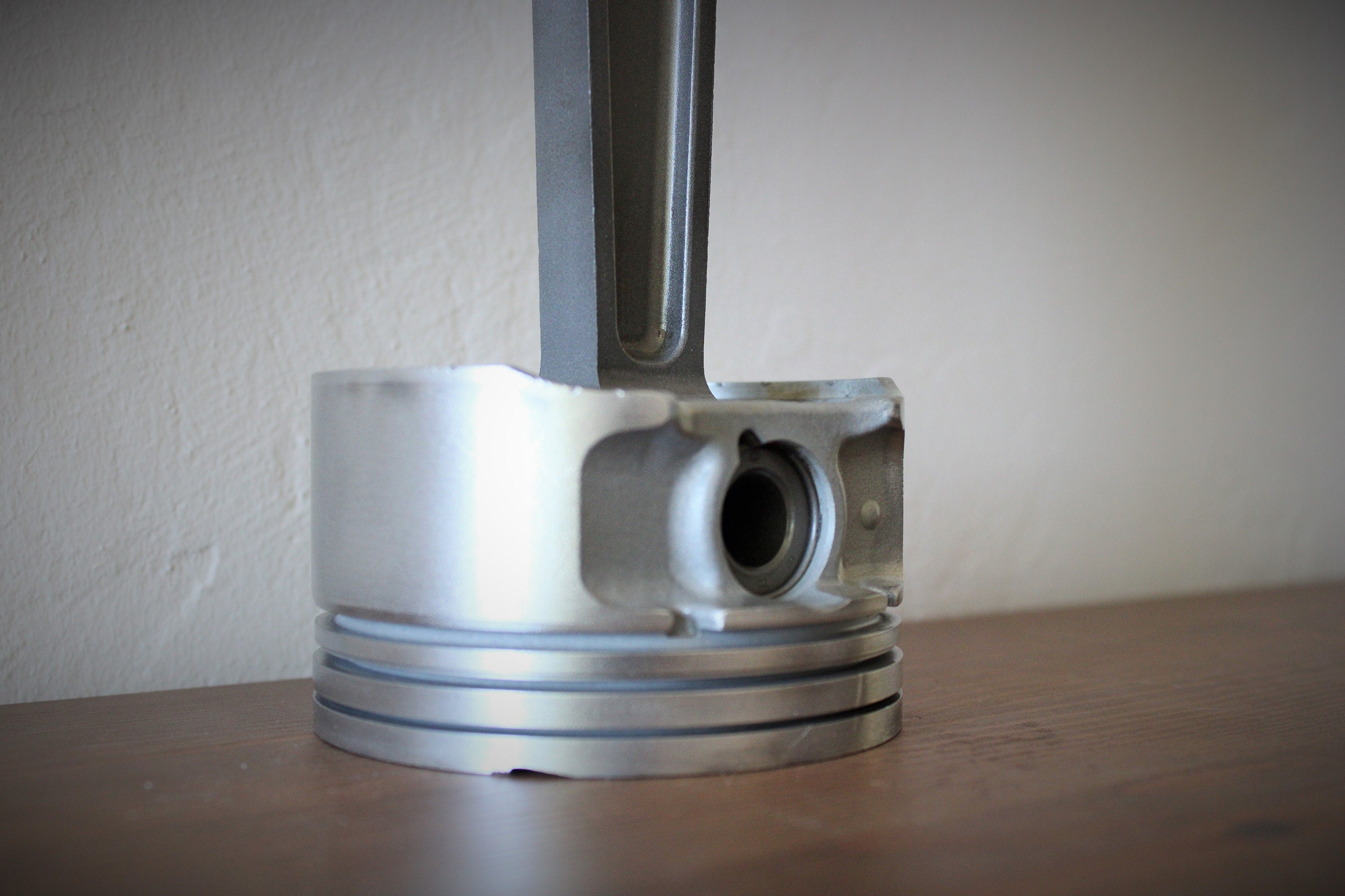 Close-up view of a piston clock made from a Jaguar car's piston, finished in gunmetal gray.