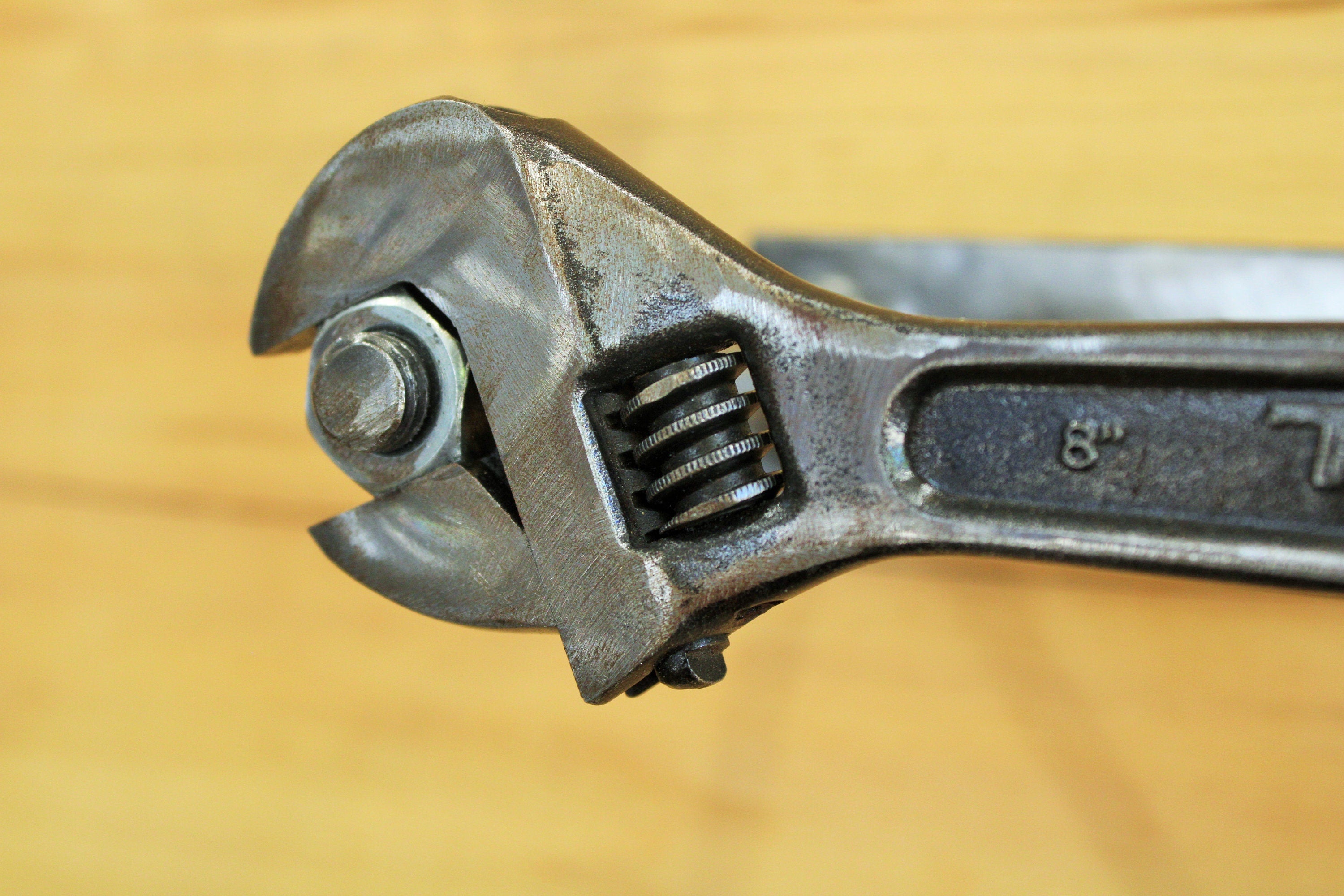 Close-up view of a wrench and nut toilet paper holder, finished in silver.