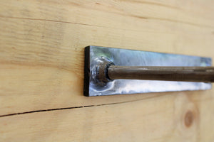 Close-up view of the wrench and nut toilet paper holder, finished in silver.