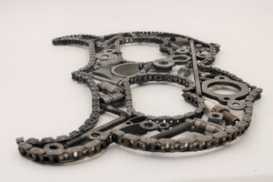 Close-up view of a letter B made out of car parts and outlined with timing chain.