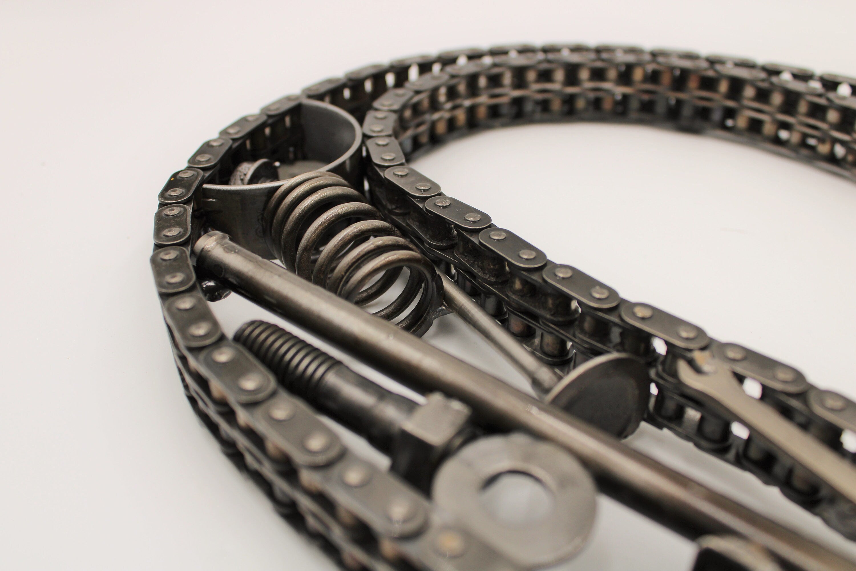 Close-up view of a letter decoration made out of car parts and outlined with timing chain.